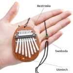 Mała kalimba w kształcie kropli trzymana na dłoni ze sznurkiem